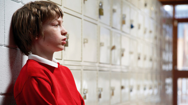 Advice Helplines Boy looking sad at school.