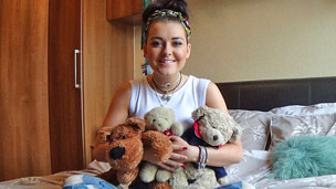 shannon sitting on her bed holding teddy bears.