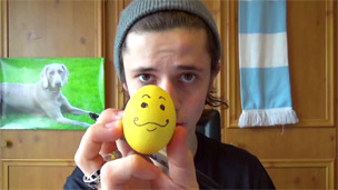 Cel holding up an egg with a smiley face drawn on it.