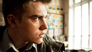 Rhydian moodily looking out of a window.