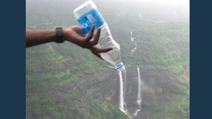 A bottle held in front of a waterfall so it looks like the water is pouring from the bottle
