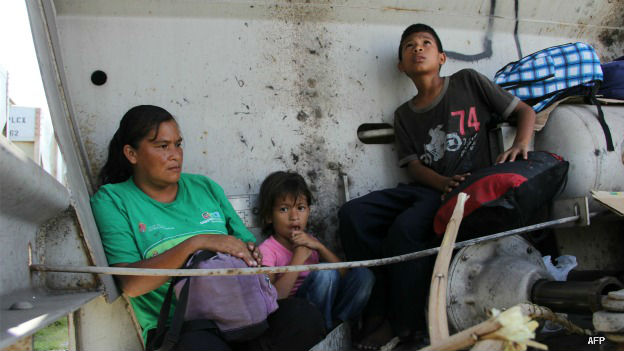 Una mujer migrante con sus hijos en el tren carguero conocido como La Bestia
