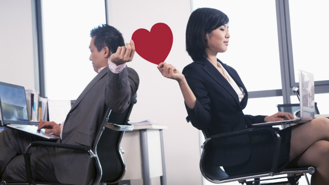 Dos personas pasándose un corazón de papel